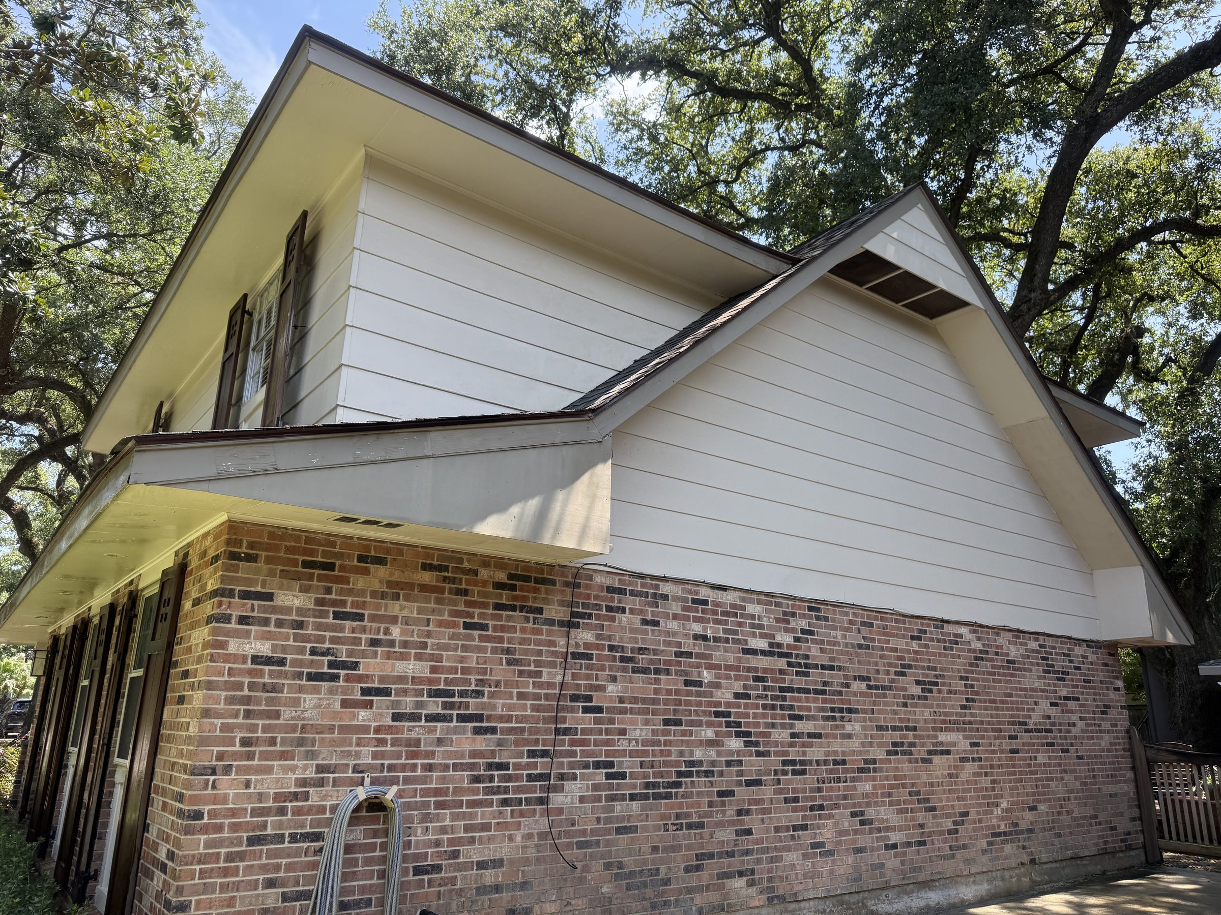 Cream siding gable over brick, washed clean on a Gretna home